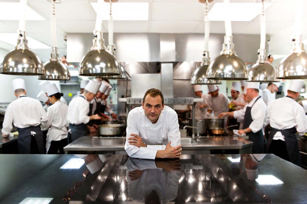 Executive head chef, Daniel Humm leaning on bench, looking at camera, in his kitchen at Eleven Madison Park Restaurant, NYC