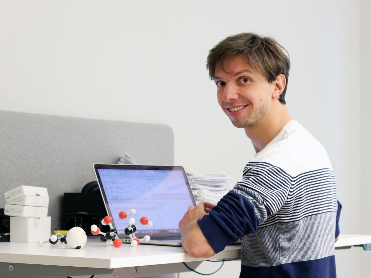 Dr Francesco Gatto, founder of Elypta, in front of laptop on desk, smiling