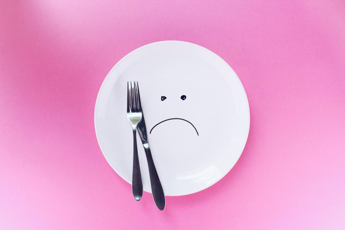 A sad face drawn on an empty white plate.