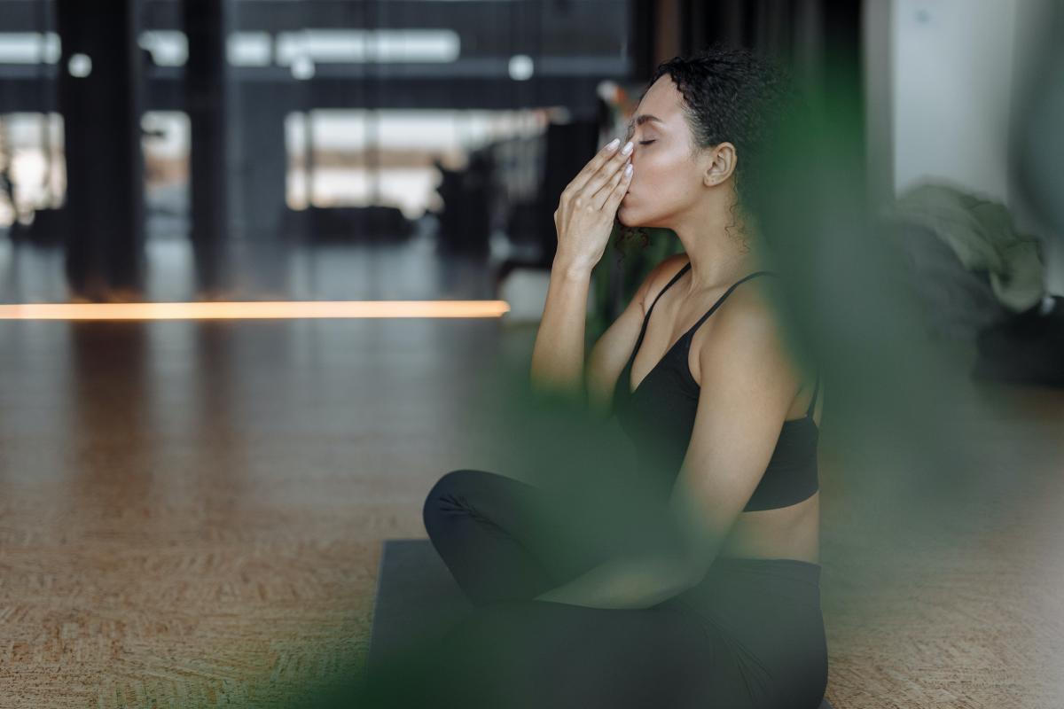 A photograph of a woman doing breathing exercises on a yoga mat