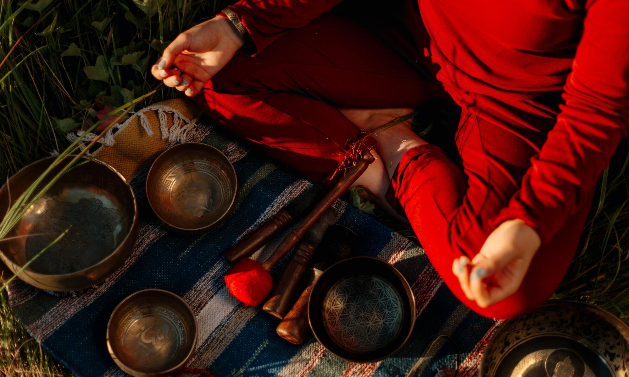 A person wearing red clothes sitting with their legs cross folded with bowls in front of them.	